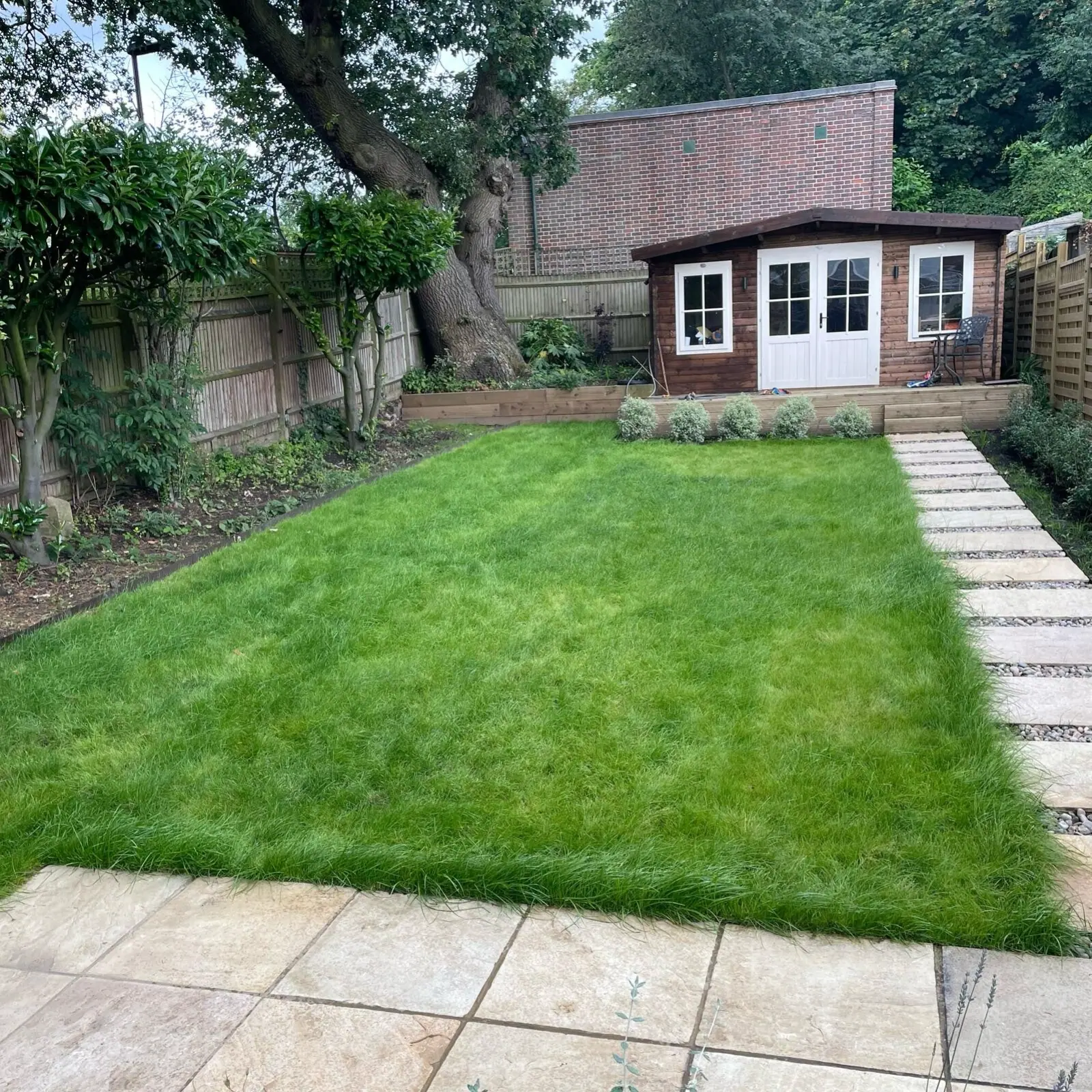 Freshly laid lawn with stepping-stone path and summerhouse after a Seeing Green garden makeover